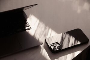 A cell phone sitting on top of a table next to a laptop